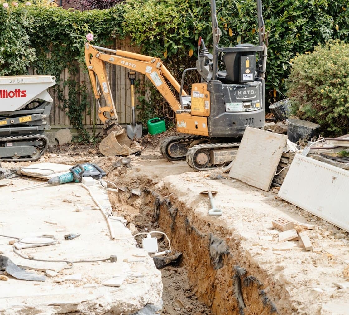 Mini excavator digging beside a house