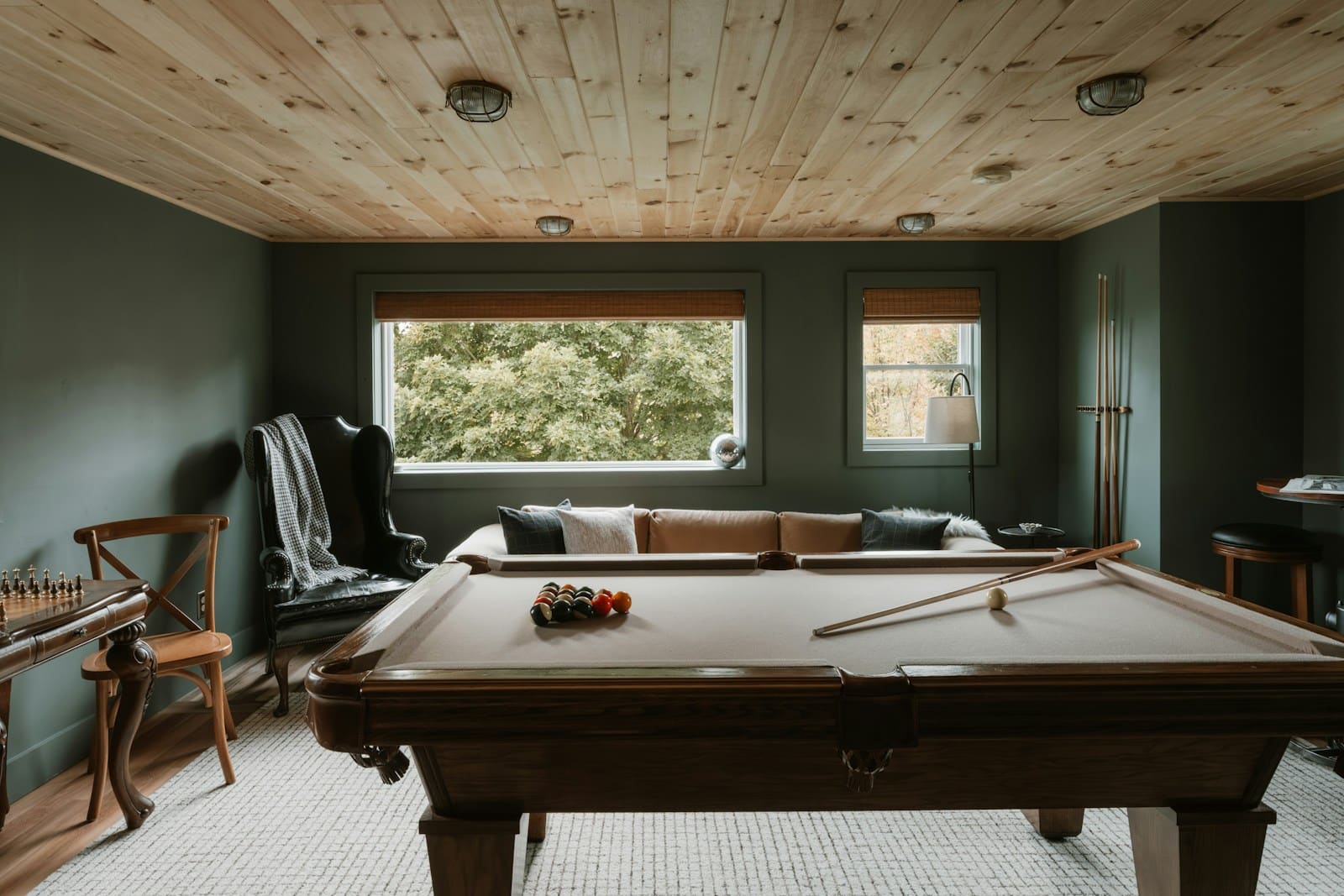 Finished basement family room with pool table, sofa and wood ceiling