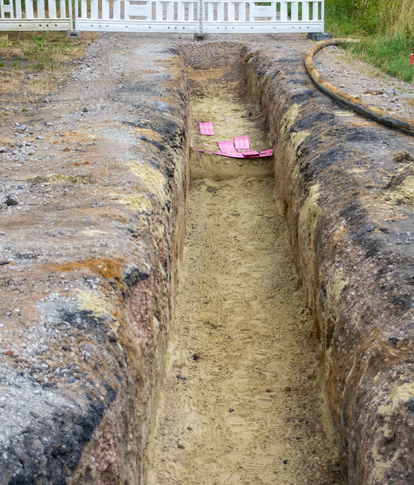 Open drainage trench beside a property, fenced off with a safety barrier